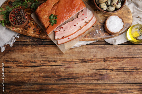 Flat lay composition with delicious smoked bacon on wooden table, space for text