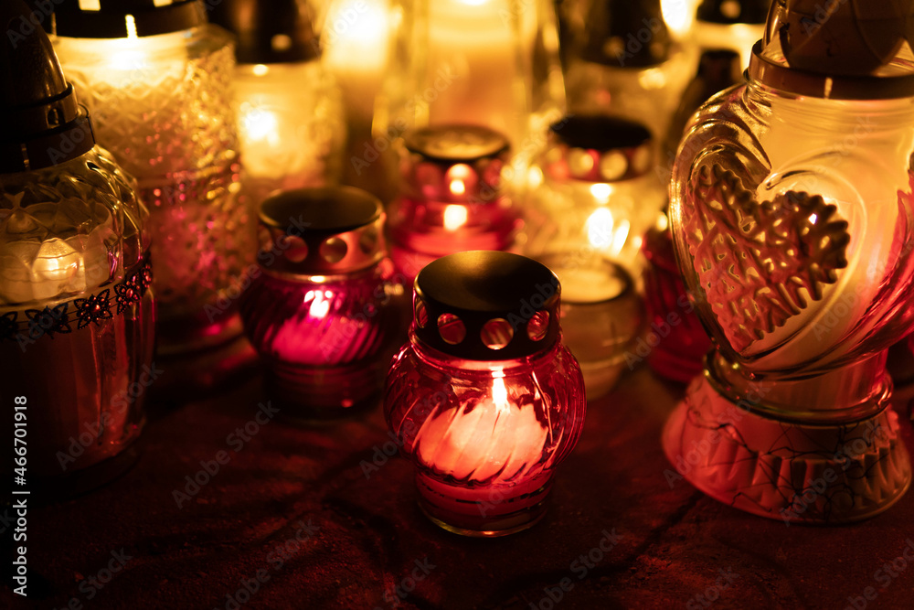 The cemetery votive candle burns with a bright light in the night. Candles burning on a cementary. Selective focus. Shallow field of depth. The cemetery votive candle burns with a bright light in the night. Candles burning on a cementary. Selective focus. Shallow field of depth.