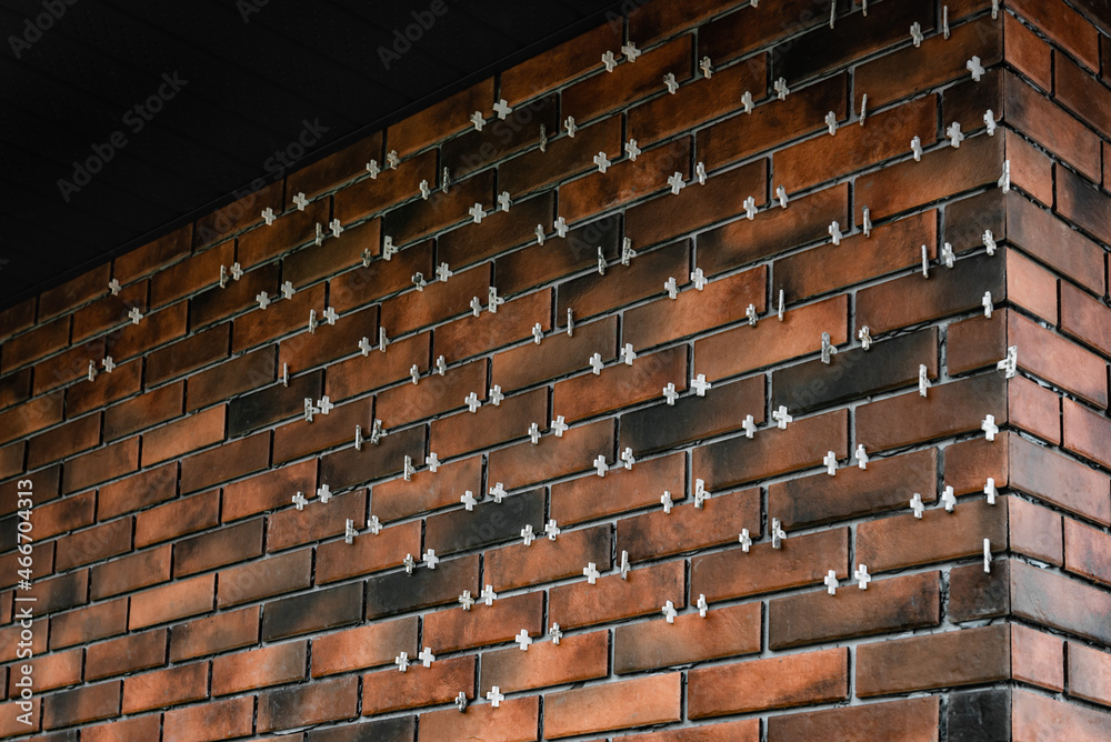 Installing the tiles in the form of brick on the wall using plastic crosses between the tiles. Installing the tiles in the form of brick on the wall using plastic crosses between the tiles.