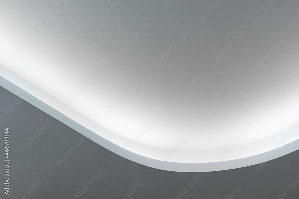 Rounded corner of the white walls and drywall suspended ceiling with integrated LED lighting