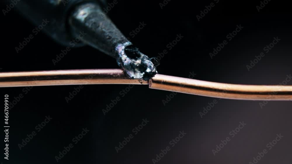 Soldering of two copper wires. Macro view. Soldering iron.Wiring repair.Tin on a soldering iron Soldering of two copper wires. Macro view. Soldering iron.Wiring repair.Tin on a soldering iron