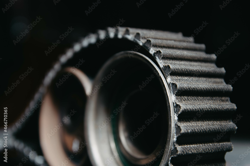 automotive timing belt on a black background. Replacement concept for idler pulleys and engine belts.