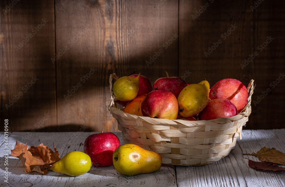 Still life: fresh fruits pears and apples in a wicker basket and on a wooden table. Drawing with light and shadow Still life: fresh fruits pears and apples in a wicker basket and on a wooden table. Drawing with light and shadow