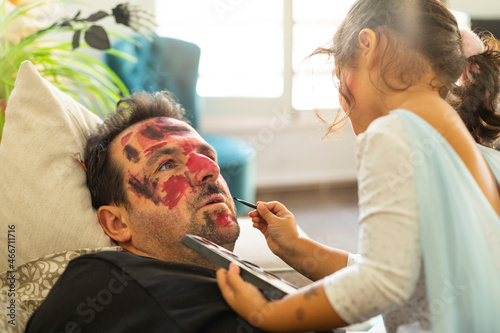 A little girl doing her father's Halloween makeup photo