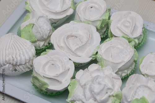Homemade marshmallows are spread out on the table surface. Marshmallow in the form of roses. Close-up shot.