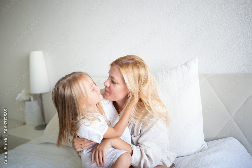 little girl hugging with mom while sitting on the bed in the bedroom