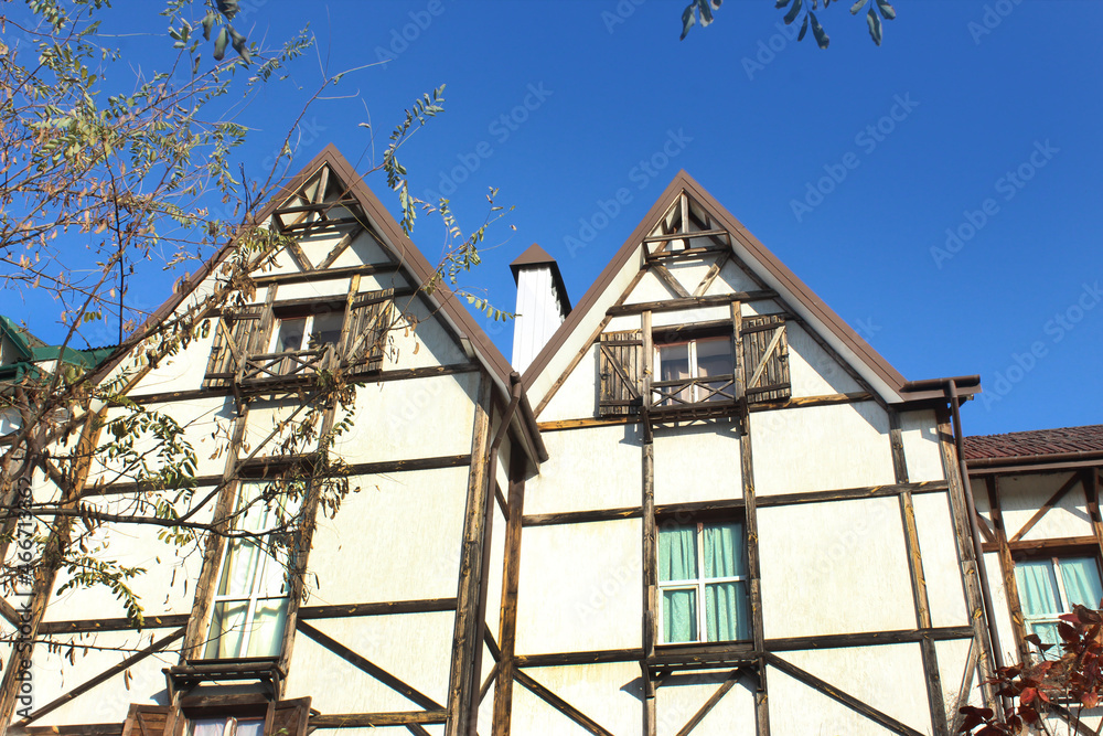 Facade of a black and white half-timbered house in European medieval style with two gabled roofs. Prussian wall with braided wooden beams