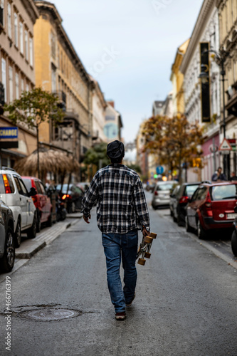 man walking in the street holding a skateboard © Rick Neves