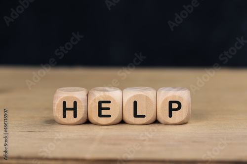 Wooden cube with the word HELP on wooden table.