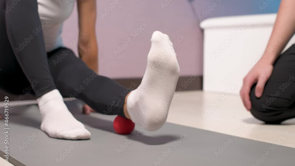 Close-up Young male massage therapist teaches client Caucasian woman patient myofascial self-massage of legs and hips using massage ball indoors. Myofasceal release Close-up Young male massage therapist teaches client Caucasian woman patient myofascial self-massage of legs and hips using massage ball indoors. Myofasceal release