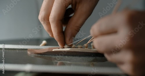 Guitar tech takes off the old strings from the guitar, luthier restrings the guitar, changing the guitar strings, , 4k 60p 10 bit photo