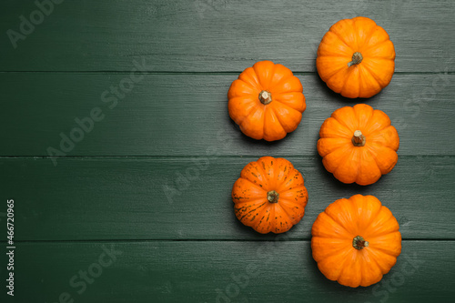 Fresh ripe pumpkins on green wooden table, flat lay. Space for text