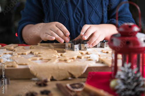 Little cute kid boy make Christmas gingerbread cookies in the New Year's kitchen.