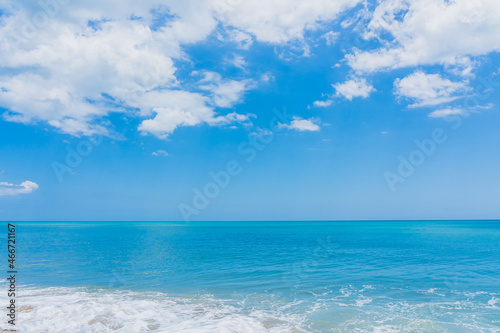 Turquoise water on the Atlantic Ocean beach merges with the blue sky with white clouds in Florida
