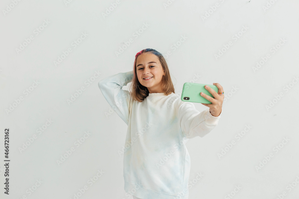 Little teenage girl with multi-colored hair is photographed on the phone, posing, takes a selfie. Child blogger
Little teenage girl with multi-colored hair is photographed on the phone, posing, takes a selfie. Child blogger