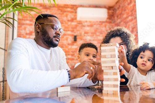 african mixed race family palying a round of jenga in cozy living room with air conditioning photo