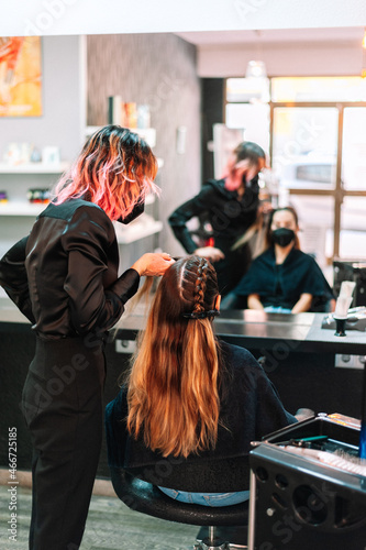 Woman hairdresser making braids to client