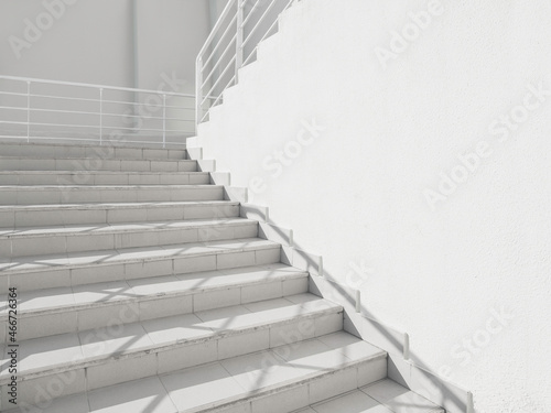 White exterior of outdoor staircase with railing. Sunlight and shadow on stone steps. Urban geometry.