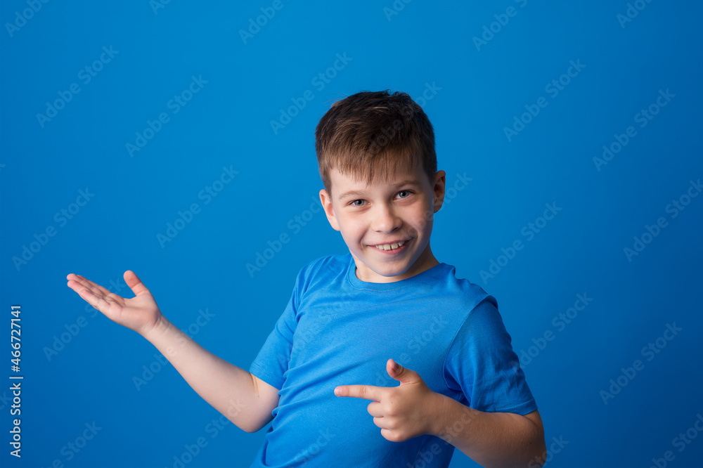 boy on a blue background points his finger to the side and free space boy on a blue background points his finger to the side and free space