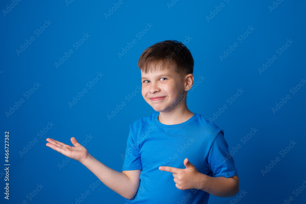boy on a blue background points his finger to the side and free space boy on a blue background points his finger to the side and free space