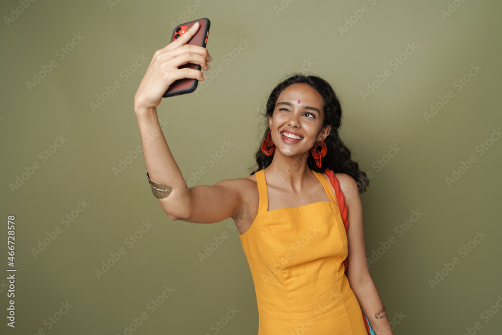 Young south asian woman winking while taking selfie on cellphone Young south asian woman winking while taking selfie on cellphone