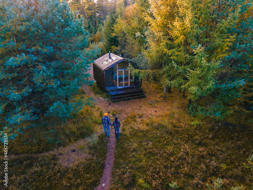 Wooden hut in an autumn forest in the Netherlands, cabin off grid , wooden cabin circled by colorful yellow and red fall trees. couple mid age European man and Asian woman in a cabin in the woods