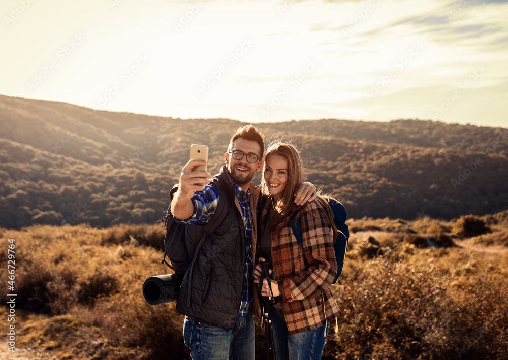 Couple with backpacks making selfie while they hiking on the mountain.