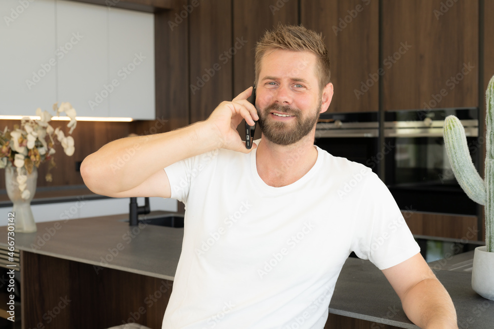 Close up of young smiling man talking on mobile in the kitchen Close up of young smiling man talking on mobile in the kitchen