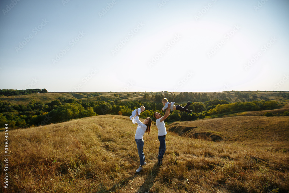 dad and mom hug children on the background of sunset and nature