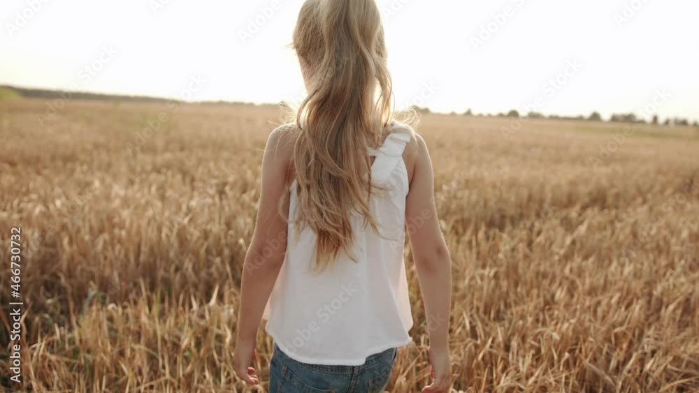A charming preschool girl in a white tunic and denim shorts walks through a wheat field in the rays sun and turns to the camera. Slow motion Stock-Video | Adobe Stock