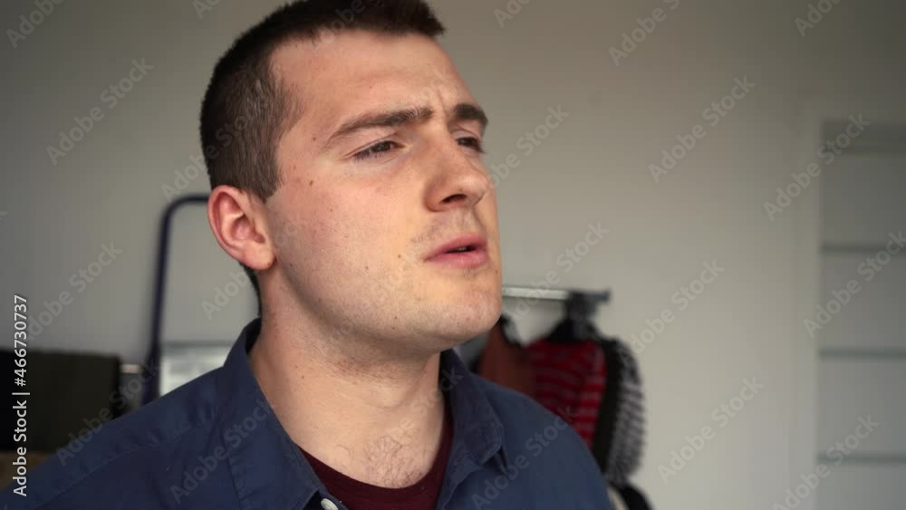 man puffs on cigarette standing in front of the window man puffs on cigarette standing in front of the window