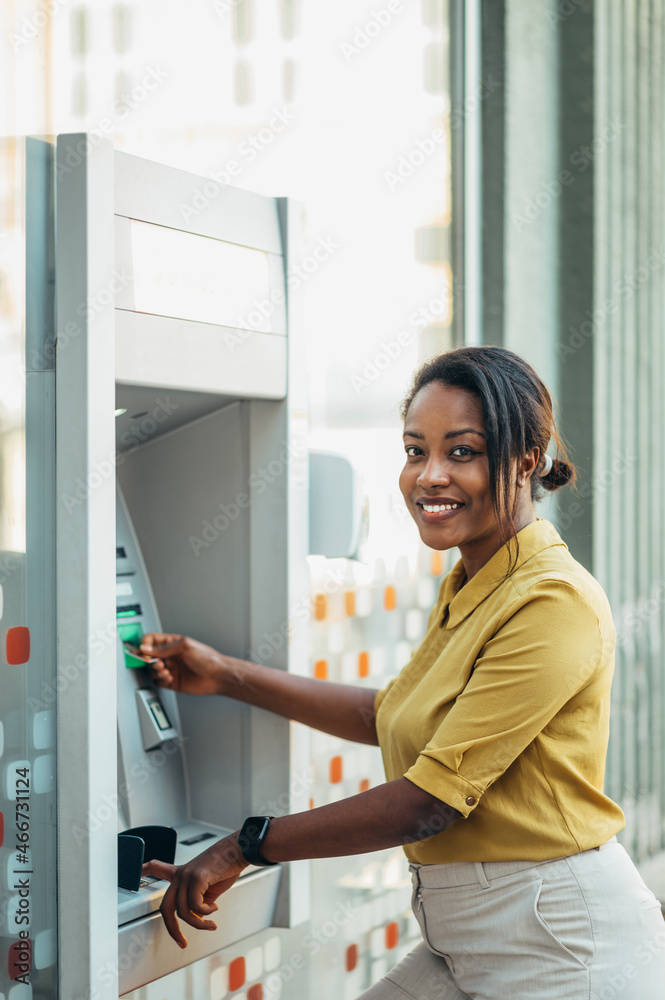 African american woman using an atm machine and a credit card African american woman using an atm machine and a credit card