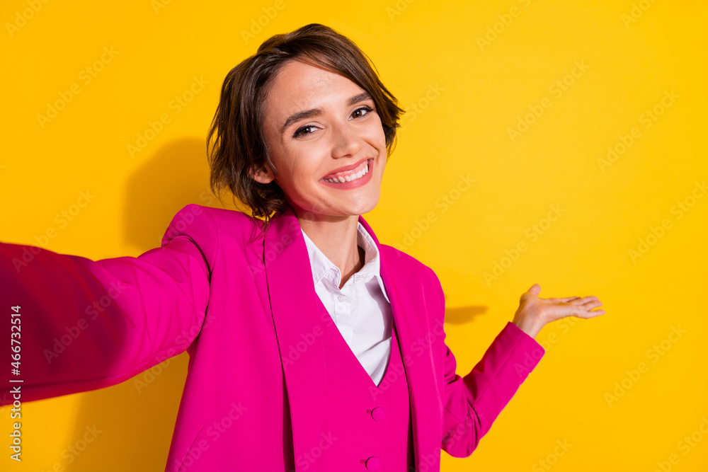 Photo of charming cute young woman dressed pink suit smiling recording self video holding arm empty space isolated yellow color background Photo of charming cute young woman dressed pink suit smiling recording self video holding arm empty space isolated yellow color background