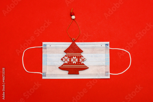 Medical mask on red background with red New Year tree. Top view with copy space, space for text. Happy New Year 2022 concept.