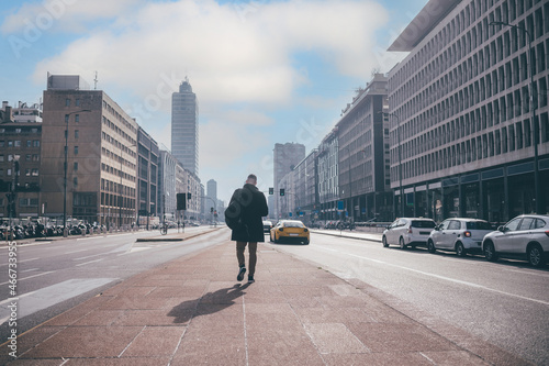 Back view young adult businessman strolling city walking away