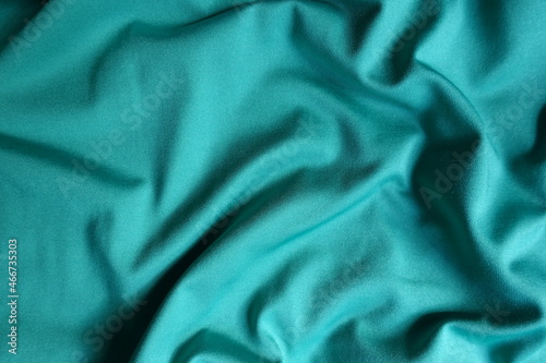 Surface of blue green polyester fabric with soft folds