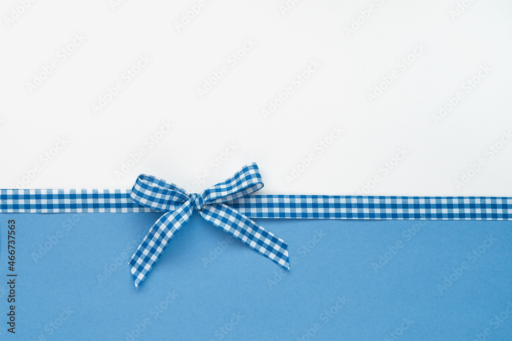 Plaid ribbon with bow on white and blue background Plaid ribbon with bow on white and blue background