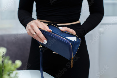 Close-up of a girl's hands with an open purse in her hands. An empty wallet is a woman with no money in her wallet. Wallet made of genuine blue leather