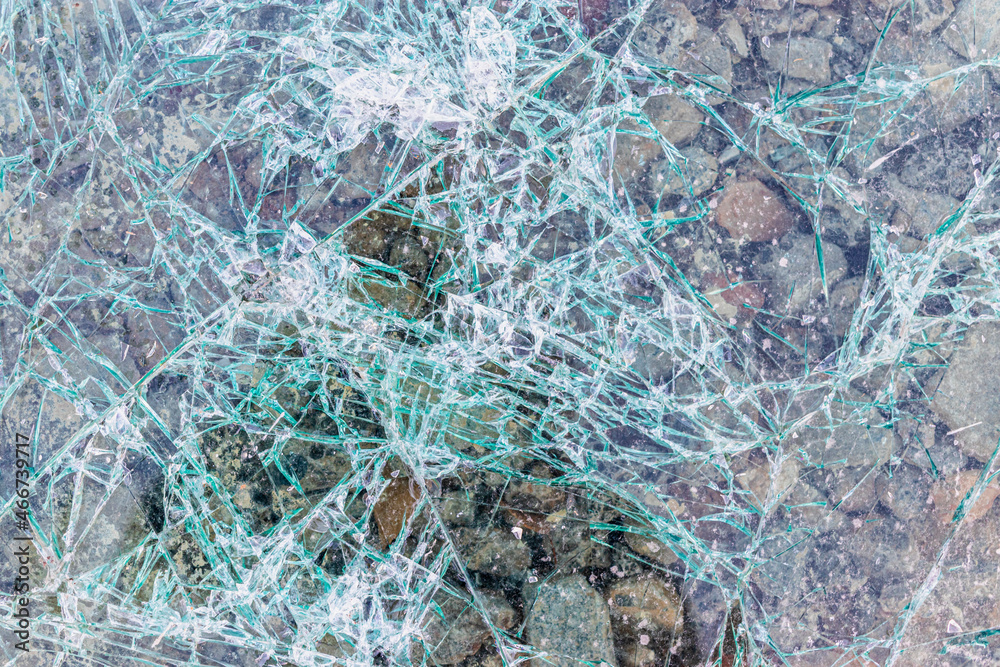 Cracked and shattered glass. Abstract texture and background. Broken glass close-up on the ground.