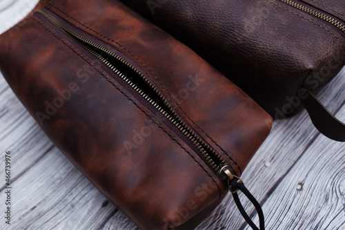 Men's personal cosmetic bag made of brown leather or a toiletry bag. Leather goods on a wooden background. Style, retro, fashion, vintage and elegance.