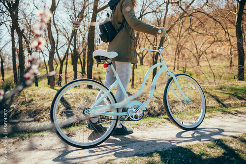Young woman with her bike walking in park