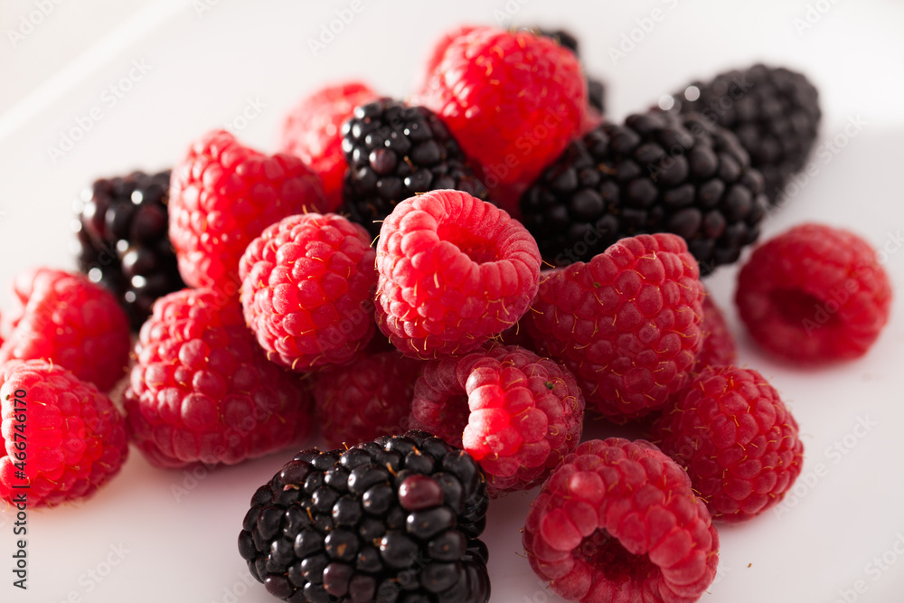 handful of raspberry and blackberry berries on white background