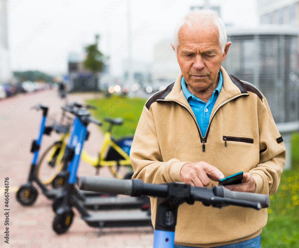 Elderly man rents an electric scooter using mobile phone Elderly man rents an electric scooter using mobile phone
