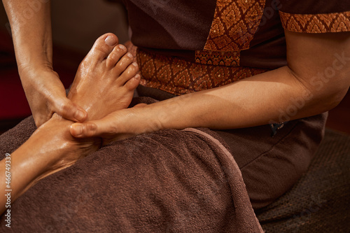 Experienced masseuse giving her client relaxing Thai foot massage photo