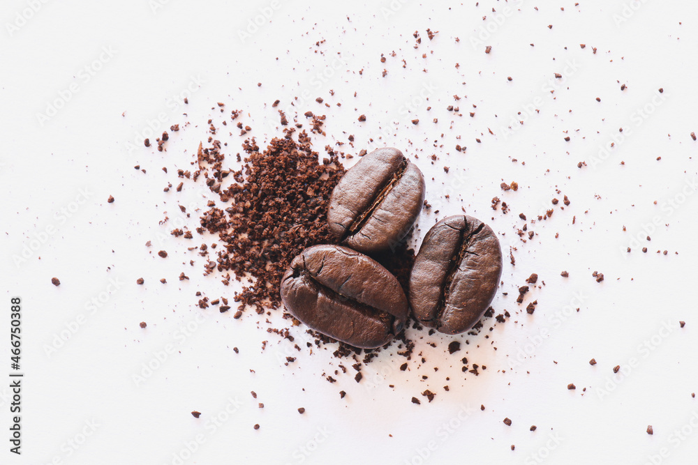 Roasted coffee beans with ground coffee on white paper background 