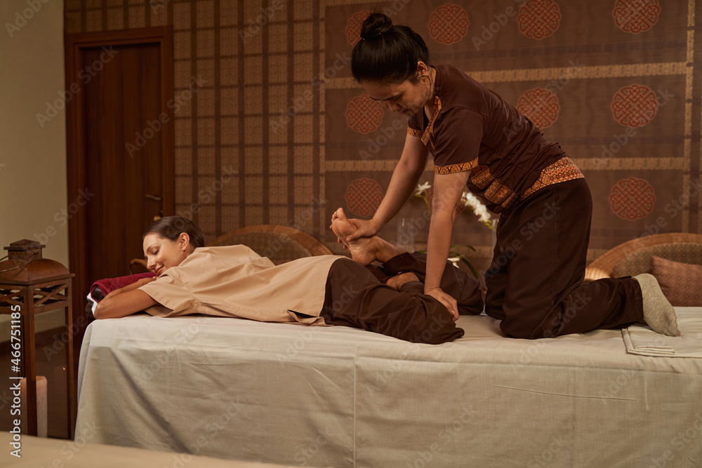Thai massage practitioner performing reverse half lotus stretch Thai massage practitioner performing reverse half lotus stretch