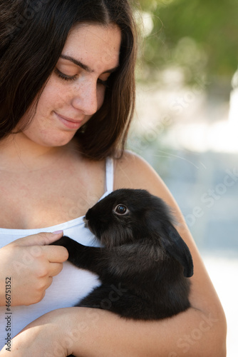 Young beautiful woman holding a black rabbit pet animal. Domestic animal caring
