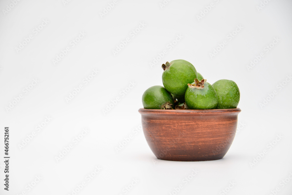 A bowl of green feijoa on the white background on the right of side. Horizontal view. A bowl of green feijoa on the white background on the right of side. Horizontal view.