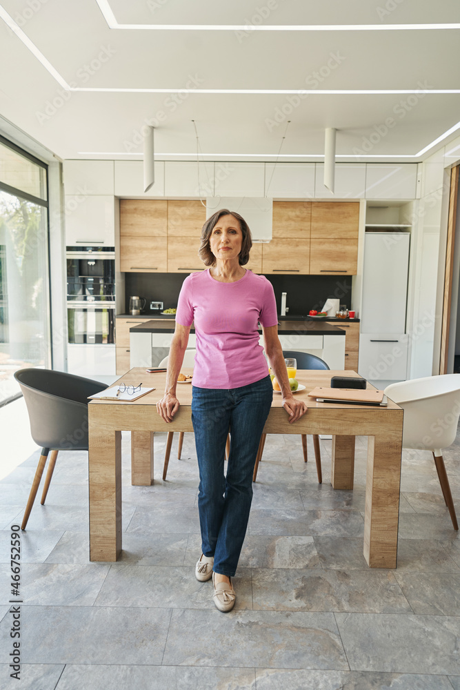 Aged woman standing in front of kitchen table Aged woman standing in front of kitchen table