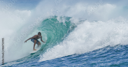 Young man surfer surfing tropical ocean wave riding barrel tube